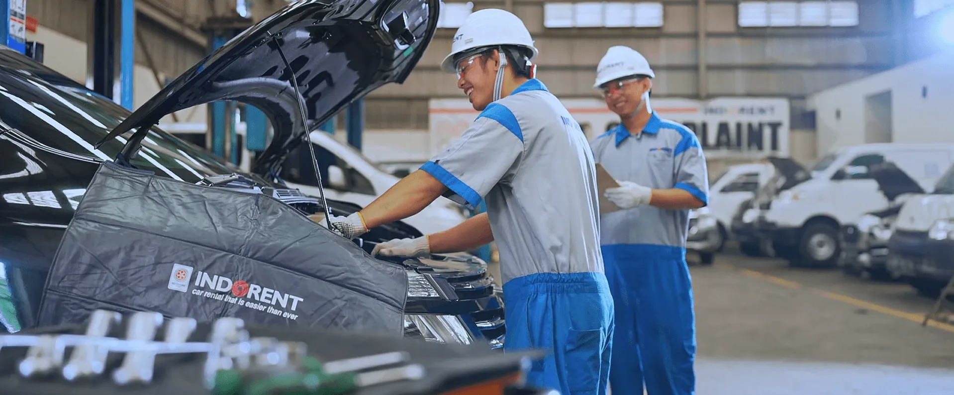 INDORENT technicians checking the engine bay of a rental car at the workshop