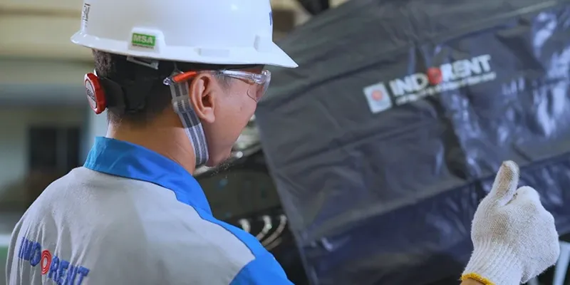 An INDORENT technician working on a rental car with a body cover