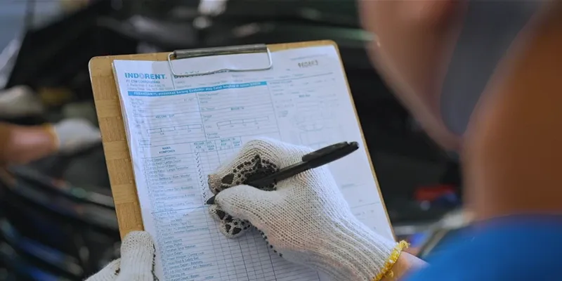 A technician filling in an INDORENT vehicle inspection sheet