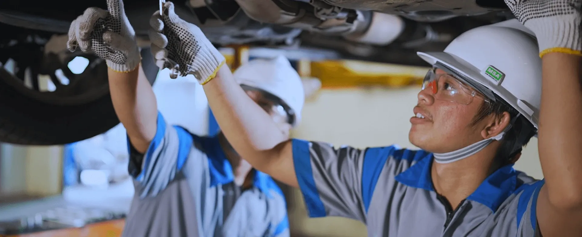 INDORENT technicians inspecting the underside of a rental car